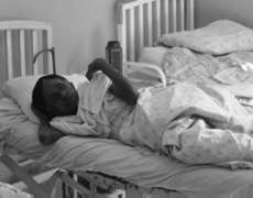 Old woman farmer watching ward rounds from her bed. Photographer: James Li, M.D.